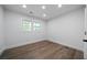 Minimalist bedroom with wood-look floors, natural light from two windows, and crisp white walls at 3904 Bakers Ferry Sw Rd, Atlanta, GA 30331