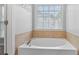 Bright bathroom features a garden tub with tile surround and window at 3525 Elder Field Ln, Cumming, GA 30040