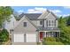 Charming two-story home featuring gray siding, a two-car garage, and a welcoming red front door at 3525 Elder Field Ln, Cumming, GA 30040