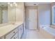 Bright bathroom featuring a double vanity, soaking tub, white cabinets, and tiled flooring for a spa-like experience at 402 Hancock Ct, Woodstock, GA 30188