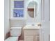 Powder room with a window, commode and vanity with an oval mirror at 402 Hancock Ct, Woodstock, GA 30188