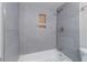 Modern bathroom featuring gray tile walls, a bathtub, and a built-in wooden niche for bath products at 4171 Whispering Forest Sw Ct, Lilburn, GA 30047