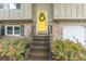 Close-up of the bright yellow front door with a wreath, brick accents, and black railing at 4171 Whispering Forest Sw Ct, Lilburn, GA 30047