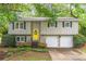 Charming home features a bright yellow door, a two-car garage, and lovely landscaping at 4171 Whispering Forest Sw Ct, Lilburn, GA 30047