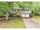 Traditional-style home with a bright yellow front door, two-car garage, and mature landscaping at 4171 Whispering Forest Sw Ct, Lilburn, GA 30047