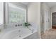 Bathroom showcasing a large soaking tub, tiled backsplash, and bright natural light at 4584 Brook Farms Dr, Duluth, GA 30096