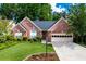 Charming brick home with manicured lawn, mature trees, lamppost and attached two car garage, creating an inviting curb appeal at 4584 Brook Farms Dr, Duluth, GA 30096