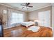 Charming bedroom featuring hardwood floors, a ceiling fan, and a sun-filled window with decorative curtains at 5370 Newport Bay Psge, Alpharetta, GA 30005