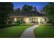 Charming home at dusk with a manicured lawn, lush greenery, and a welcoming walkway to the front door at 5945 W Andechs Smt, Johns Creek, GA 30097