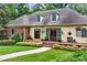 Charming home with a manicured lawn, lush greenery, and a welcoming brick-lined porch to the front door at 5945 W Andechs Smt, Johns Creek, GA 30097