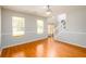 Living room with hardwood floors, three windows, and a view into the foyer with staircase at 1583 Rogers Crossing Dr, Lithonia, GA 30058
