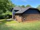 Newly sided back exterior with grass and a patio, accented by mature trees and landscape at 323 W Claiborne Ct, Marietta, GA 30066