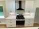 Modern kitchen featuring stainless steel range and hood with sleek white cabinets and quartz countertops at 323 W Claiborne Ct, Marietta, GA 30066