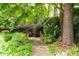 Stone walkway and wooden bench surrounded by manicured bushes and large tree at 7590 Chaparral Dr, Atlanta, GA 30350
