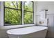 Bright bathroom showcasing a soaking tub with a view of lush greenery through a large window at 136 Beutell St, Norcross, GA 30071