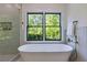 Bright bathroom featuring a soaking tub, bronze fixtures, a frameless shower, and a nature view at 136 Beutell St, Norcross, GA 30071