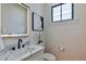 Chic half-bathroom featuring modern fixtures, illuminated mirror, stylish artwork, and a bright, windowed space at 136 Beutell St, Norcross, GA 30071