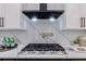 Gas range cooktop with stainless steel hood and tile backsplash in a modern kitchen design at 136 Beutell St, Norcross, GA 30071