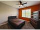 Bedroom with a bed, dark wood dresser, orange accent wall, and natural light at 3784 The Great Dr, Atlanta, GA 30349
