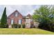 Traditional brick home featuring manicured lawn, stone accents and mature landscaping at 3784 The Great Dr, Atlanta, GA 30349