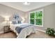 Bright bedroom with large window overlooking trees, side tables, lamps, and bed with blue accents at 10 Berryhill Se Pl, Cartersville, GA 30121