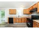 Well-lit kitchen with wood cabinets, black appliances, and sliding glass door to deck at 1034 Sandy Ridge Rd, Mcdonough, GA 30252