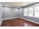 This bedroom features wood floors, three windows, and gray walls at 10664 Sandpiper Rd, Jonesboro, GA 30238