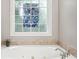 Relaxing bathtub with a decorative window and a tiled surround at 2297 Herring Woods Way, Grayson, GA 30017