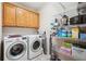 Functional laundry room with washer, dryer, upper cabinets, and shelving for ample storage at 2297 Herring Woods Way, Grayson, GA 30017