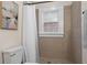 Cozy bathroom featuring tiled walls and floors, framed window, shower with curtain, and tasteful wall art at 242 12Th Ne St # 14, Atlanta, GA 30309