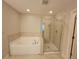 Bright bathroom features a soaking tub and a glass-enclosed shower with neutral tile surround at 8265 Village Pl, Suwanee, GA 30024