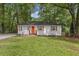 Charming home featuring an orange front door, complemented by white-painted brick and lush green landscaping at 1927 Willa Way, Decatur, GA 30032