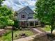 Two-story home featuring stone accents, blue siding, landscaped front yard, and a charming covered front porch at 207 Harmony Lake Dr, Canton, GA 30115