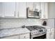 Close up on gas cooktop and oven, granite countertop, subway tile backsplash, and white cabinetry at 207 Harmony Lake Dr, Canton, GA 30115