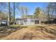 Backyard view of the house featuring a grassy lawn, trees, and gray painted siding at 1602 Sycamore Nw Dr, Kennesaw, GA 30152