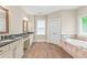 A bathroom features double sinks with granite countertops, a soaking tub and wood tile floors at 3394 Bryerstone Se Cir, Smyrna, GA 30080