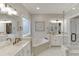 Elegant bathroom featuring dual vanities, soaking tub, and glass-enclosed shower with modern fixtures and neutral color palette at 4355 Old Hamilton Mill Rd, Buford, GA 30518