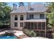 Back exterior of a two-story house featuring a screened porch, pool and hot tub surrounded by trees at 4567 Brigade Ne Ct, Roswell, GA 30075