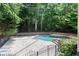 Private backyard featuring a sparkling pool, stone retaining wall, and lush greenery at 4567 Brigade Ne Ct, Roswell, GA 30075
