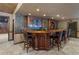 Elegant home bar featuring dark wood finishes, seating for five, and glass shelving for display at 4567 Brigade Ne Ct, Roswell, GA 30075