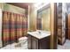 Cozy bathroom with a single sink vanity, toilet, framed mirror, and a shower with patterned curtain at 4567 Brigade Ne Ct, Roswell, GA 30075