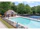 Community pool surrounded by chairs, greenery, and an adjacent tennis court at 4567 Brigade Ne Ct, Roswell, GA 30075