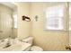 Cozy half bathroom featuring a wallpaper design, toilet, sink, mirror, and window at 1935 Shrader Ct, Lawrenceville, GA 30044