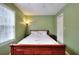 Bright bedroom featuring a wooden bed frame, green walls, and a window with blinds offering natural light at 1935 Shrader Ct, Lawrenceville, GA 30044