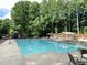 Community swimming pool surrounded by lounge chairs and tall trees at 1935 Shrader Ct, Lawrenceville, GA 30044