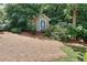 A cute storage shed with a white door is nestled in a wooded area at 1935 Shrader Ct, Lawrenceville, GA 30044