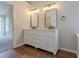 Bathroom featuring double vanity with framed mirrors, white cabinets, and wood-look floors at 4565 English Oaks Ln, Lilburn, GA 30047