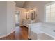 Bathroom with a soaking tub, double vanity, wood-look flooring, and a view of the Primary bedroom at 4565 English Oaks Ln, Lilburn, GA 30047
