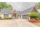 A beautiful home with a brick facade, a gray garage door, and manicured bushes at 4565 English Oaks Ln, Lilburn, GA 30047