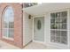 Inviting front entrance with decorative sage door, sidelight, transom window, and brick accent wall at 4565 English Oaks Ln, Lilburn, GA 30047
